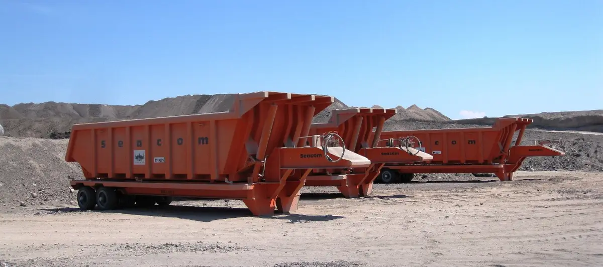 Three orange Seacom tipping roll trailers